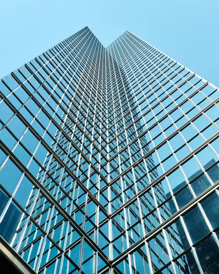 Fachada de vidro de um edifício corporativo vista de baixo para cima, sem marca visível