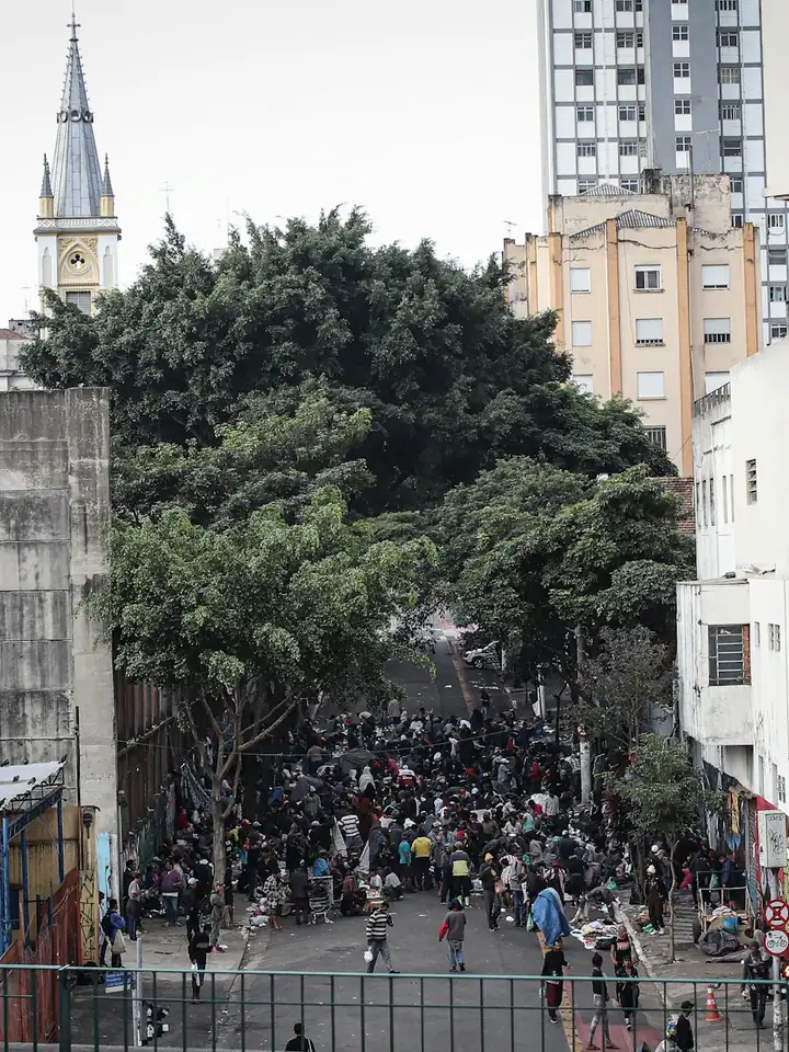 Multidão numa rua do centro de São Paulo, vista de cima, entre prédios e uma torre de igreja.